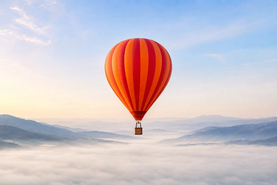 A red and orange striped hot air balloon above a misty valley