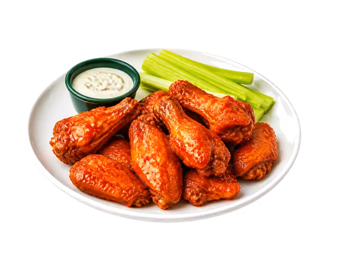 Plate of buffalo wings served with celery sticks and a creamy dip