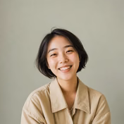 Smiling young woman with short dark hair wearing a beige jacket.