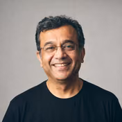 Smiling man with glasses wearing a black t-shirt.