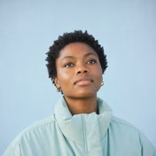 Young woman with hoop earrings and a light jacket looking up.