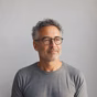 Portrait of a man with short curly hair and glasses looking to the side.