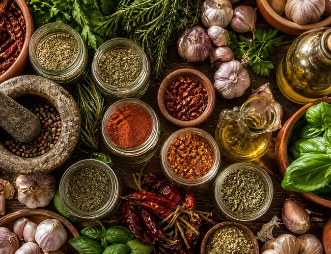 Spice jars, olive oil and fresh herbs on a work bench.