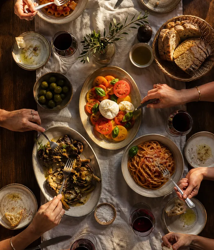 A shared table seen from above, wine glasses and plates.