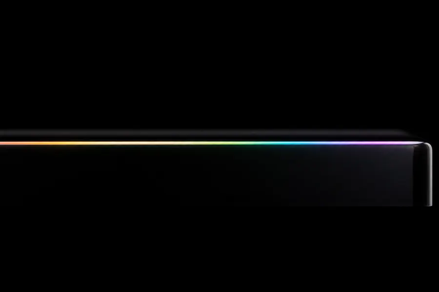 The edge of a dark glass panel catching a rainbow reflection