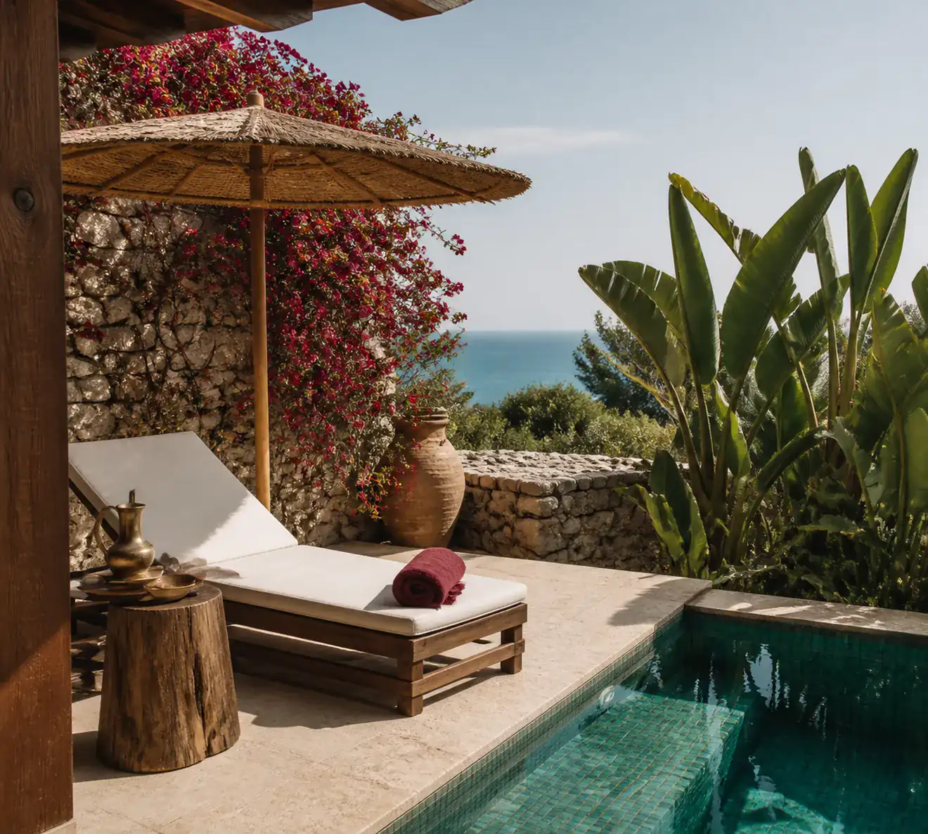 A villa terrace: a turquoise pool bordered with stone, teak loungers and bougainvillea.