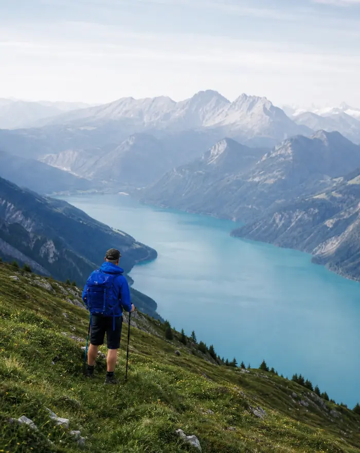 Walker on a green slope above a mountain lake