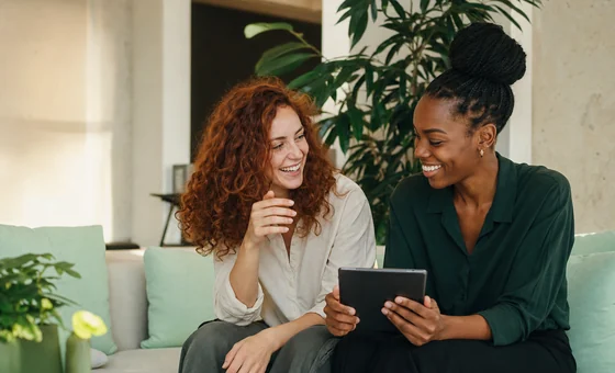 Two colleagues laughing together on a sofa