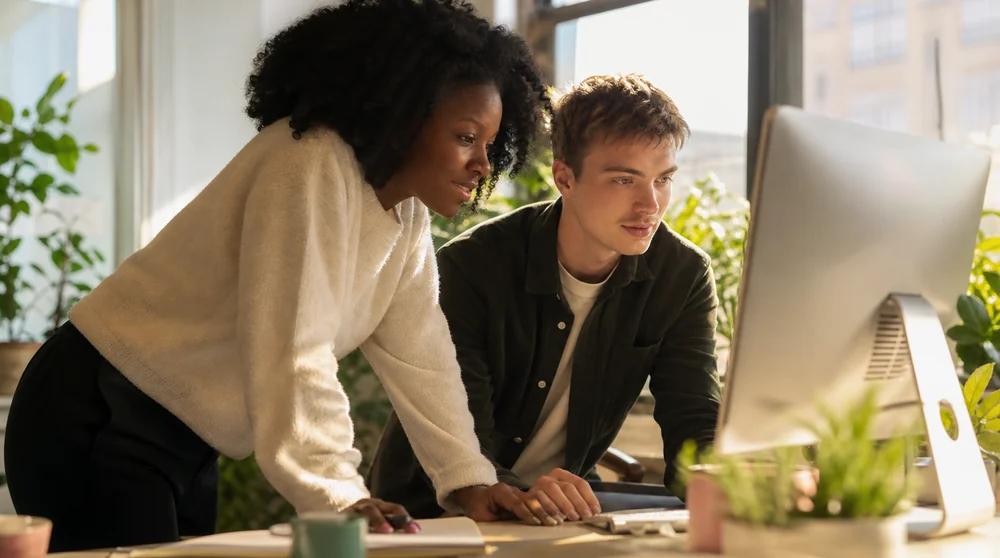 Two colleagues at a computer in a plant-filled office