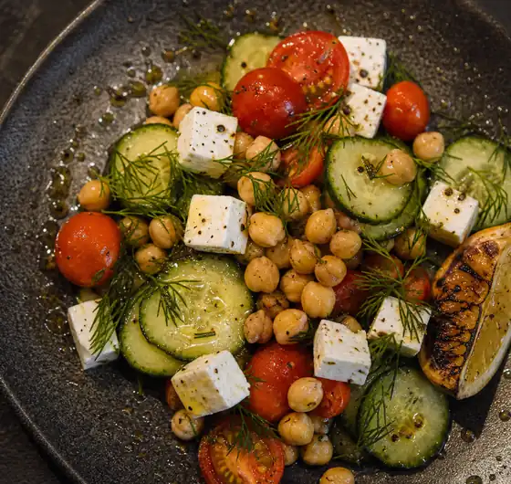 Feta, chickpeas and tomatoes on a dark plate