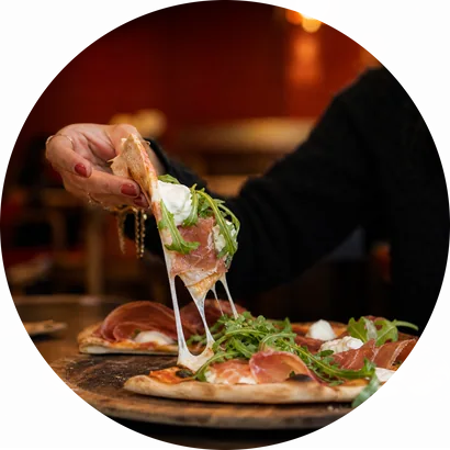 A slice of prosciutto pizza being lifted