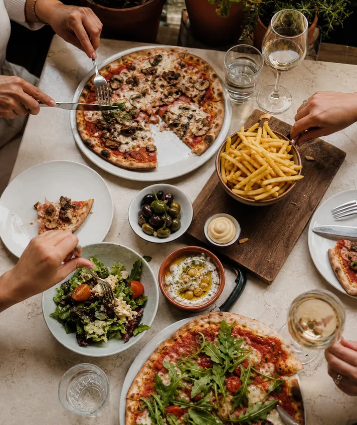 A table covered with pizzas, fries and salads