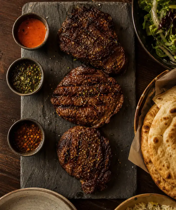 A slate board of grilled beef and flatbread