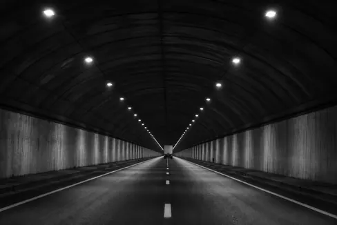 A freight truck inside a lit road tunnel at night.