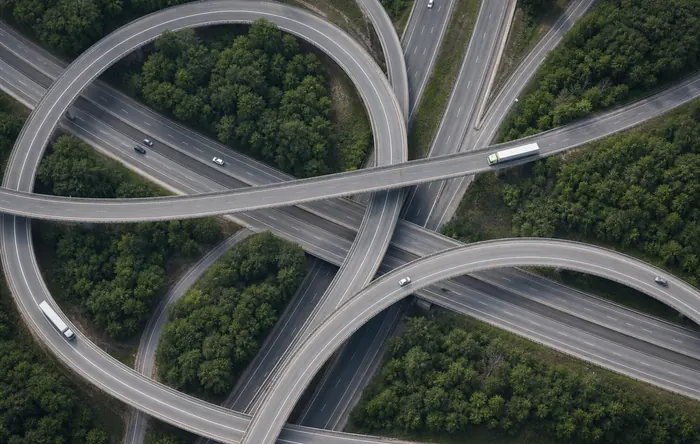 Aerial view of a motorway interchange with freight trucks curving through it.